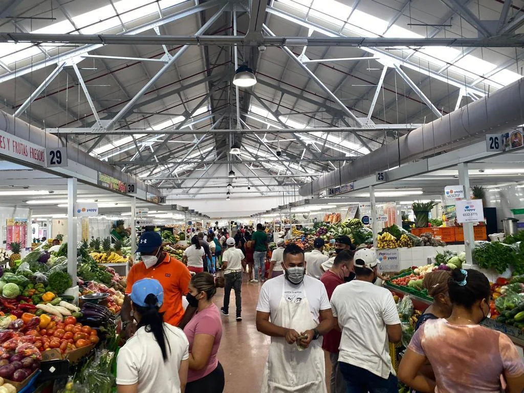 Pasillo de un mercado de frutas y verduras lleno de gente